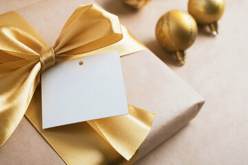 Gift box with blank card mockup on golden background. Christmas or New year greeting card. Close...