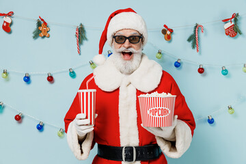 Young old man in 3d glasses Christmas hat red suit watch movie film hold bucket of popcorn cup of...