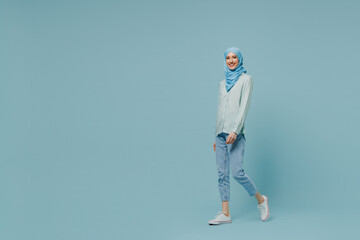 Full body fun young arabian asian muslim woman in abaya hijab hold hands crossed folded walk go...