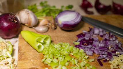 VEGETABLES TO SEASON TROPICAL FOOD, ONION, GARLIC, PEPPER, OREGANO AND PARSLEY ON CHOPPING BOARD WITH CHEF KNIFE