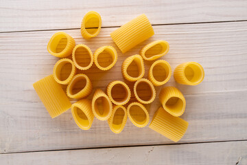 Raw organic cannelloni pasta on a wooden table, close-up, top view.