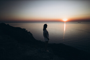 Silhouette of a girl on the background of the sea during sunset