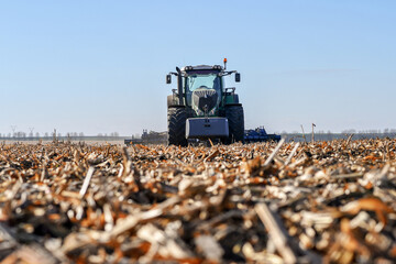 Close up of tractor with equipment for disking soil after corn harvesting. Selective focus.