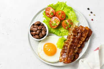 Egg and bacon, fresh tomatoes, beans, English breakfast on plate. Top view, copy space.