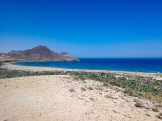 beautiful scene of a calm sea, under a blue sky with clouds and surrounded by a mountain with vegetation.