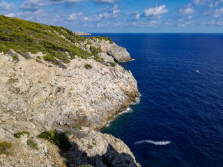 beautiful scene of a calm sea, under a blue sky with clouds and surrounded by a mountain with vegetation.