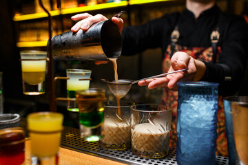 A bartender makes a cocktail over the marble bar counter