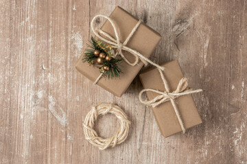 Fototapeta na wymiar gift boxes wrapped in paper with a lace bow and a small ornament, wooden textured background, texture detail in studio, celebration wallpaper