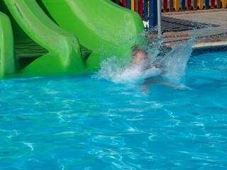 A little girl is riding a water slide in the water park.