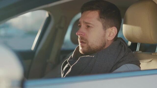 Ill caucasian businessman manager driving to work sitting inside car and sneezing allergy. Flu, fever and sore throat. Coronavirus symptoms. Pandemic. Healthcare.