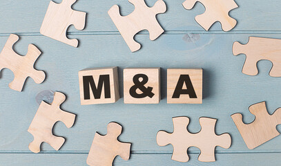 Obraz premium Blank puzzles and wooden cubes with the text M AND A lie on a light blue background.