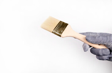 A gloved hand holds a paintbrush. Man paints the walls