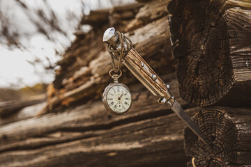 an old watch hanging from a knife stuck in an old cottage
