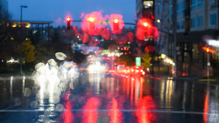 Heavy rain obscured traffic lights and car headlights at a road junction at dusk