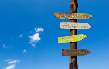 Colorful wooden signs with distances to other cities against a blue sky