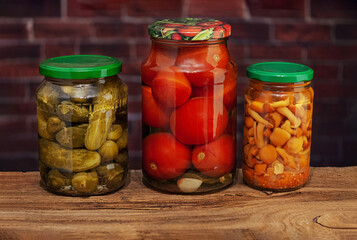 jars with homemade canned cucumbers and tomatoes and mushrooms