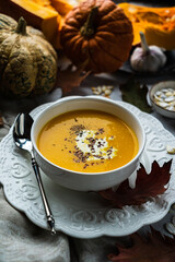pumpkin cream soup on a background of cut pumpkins, garlic, seeds, leaves