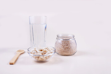 of the husk and psyllium capsules and a glass of water on a light background.