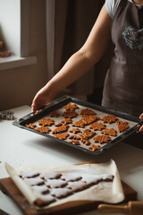 Baker is holding a baking sheet with gingerbread cookies.