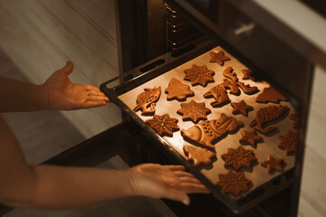 Baker places a baking sheet with gingerbread cookies in the oven