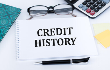 Credit history text on notepad on white background near glasses, pen, calculator
