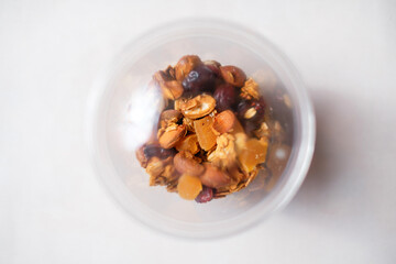 Muesli in a transparent plastic container. Healthy takeaway granola food. Top view.