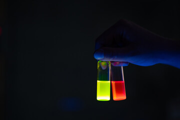 A woman researcher holding chemistry photochemical reaction glass vials in a organic laboratory -...