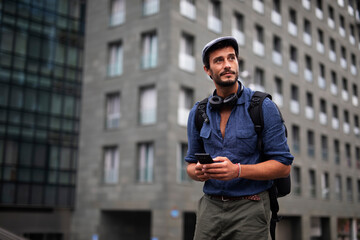 Young stylish man using the phone outdoors. Fashion happy guy enjoy outdoors.