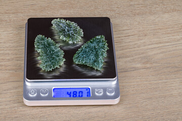 Weighing of rare moldavite gems by scale with digital display on a wood background. Green vitreous...
