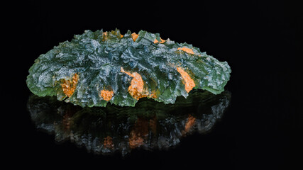 Natural green moldavite gem with reflection on black background. Beautiful meteoric glass with...