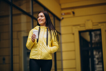 Young woman drinking coffee and walking in the street