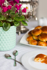 Russian traditional teaparty with samovar and pies or pirozhki with apple jam on white platter on white tablecloth 