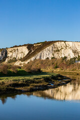 Fototapeta na wymiar Looking along the River Bank in Lewes at Chalk Cliffs and Their Reflections in the Water