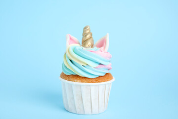 Cute sweet unicorn cupcake on light blue background