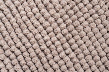 Naklejka premium The repetitive pattern of a bathroom rug for background. Thick fluffy microfiber floor mat from chenille fabric