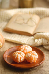 Peeled tangerines, butternut squash, open book, reading glasses and cozy blanklet. Hygge at home. Selective focus.