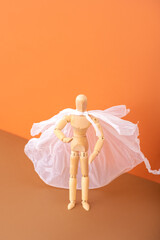 Wooden mannequin miniature doll in a cellophane cape on beige background Zero waste concept 