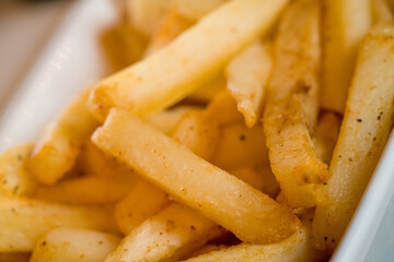 Close Up of Seasoned Golden Yellow French Fries in Basket with Pepper and Salt