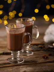 Festive composition - two glass cups of cocoa on a black background with golden lights. Decor. Romantic date, restaurant, cafe, pastry shop, advertising, Valentine's Day. Close-up.