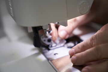 The workplace of a seamstress. The dressmaker works on a sewing machine. A tailor sews clothes at...