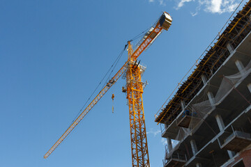 Fototapeta na wymiar Tower crane on a background of blue sky. Construction crane at a construction site. Heavy Duty Lifting Equipment