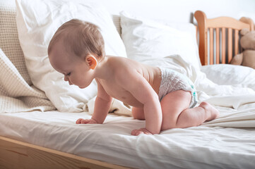 Portrait of beautiful baby 11 months old in diaper on bed close-up. Skincare, healthcare concept for children.