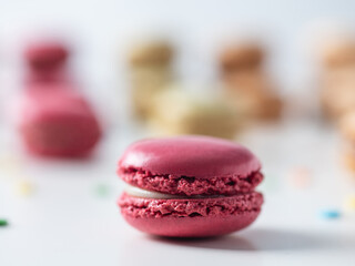 Multicolored macaroon cookies on the white background. Pink macaroon in the foreground