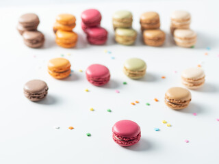 Multicolored macaroon cookies on the white background. Pink, orange, and coffee macaroon in the foreground