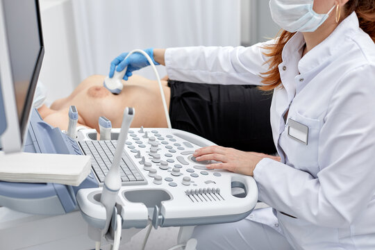 Female doctor gives the patient a female abdominal ultrasound. Ultrasound scanner in the hands of a doctor.