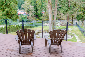 Obraz premium Two chairs on porch with a foret river view.