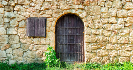 Fototapeta na wymiar Wall of stones and authentic door of house. Travel concept.