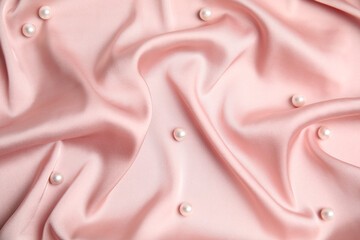 Many beautiful pearls on delicate pink silk, flat lay