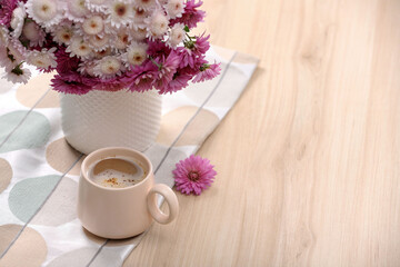 Cup of hot coffee and beautiful bouquet on wooden table. Space for text