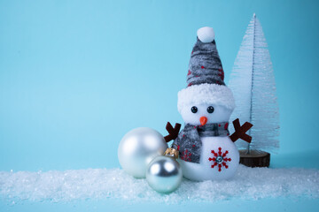 Fototapeta premium Snowman, gift, Christmas tree, Christmas ball on white snow on a turquoise background. Christmas New Year card. Place for an inscription.